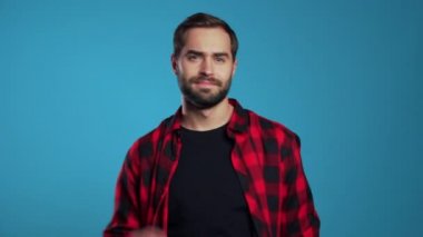 Sakallı bir adam eğleniyor, gülümsüyor, kafasıyla dans ediyor ve stüdyoda mavi arka planda parmaklarını şaklatıyor. Müzik, dans konsepti