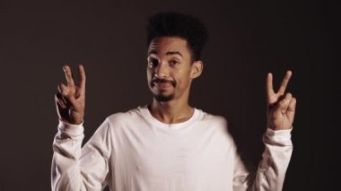 Elleri tırnak işareti gibi olan Afrika kökenli Amerikalı bir adam, parmaklarını koyu arkaplanda izole bir şekilde büker. Çok komik, ironi ve alaycılık konsepti..