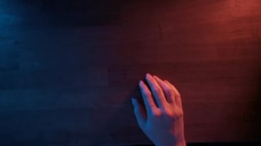 Genç bir kadın neon ışıkta bir bardak bira içiyor. Geceleri mutfakta alkollü içki içen tanınmamış bir kadın. Üst görünüm.