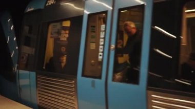 Şubat, Stockholm, İsveç. Metro treni hareket ediyor. Modern metro istasyonundan yavaş hareket eden yeraltı treni. Yolunu takip eden insanlarla dolu vagonlar.