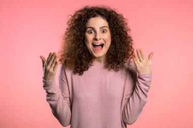 Kıvırcık saçlı bir kızın portresi, çok hoş bir etki gösteriyor. Şaşırmış, heyecanlı, mutlu kadın. Pembe arka planda şok olmuş güzel bir kadın modeli..