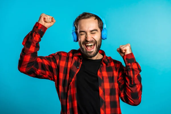 Knappe man met een koptelefoon die op een blauwe achtergrond danst. Feest, muziek, lifestyle, radio en disco concept. — Stockfoto