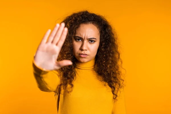 No, never, pretty curly woman disliking and rejecting gesture by stop palm sign. Portrait of young successful confident girl isolated on yellow background. — Stock Photo, Image