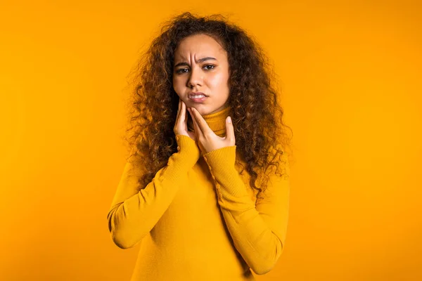 Mujer bonita joven con dolor de muelas en el fondo amarillo del estudio. Dolor de muelas, problemas dentales, estomatología y concepto de medicina — Foto de Stock