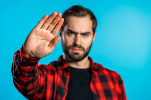 No, never, handsome brunette man disliking and rejecting gesture by stop sign. Portrait of young successful confident guy isolated on blue — Stock Photo, Image