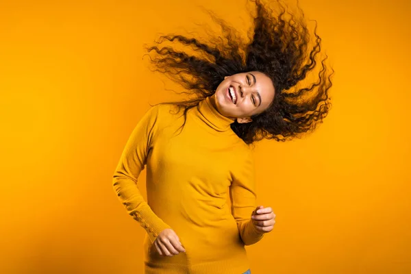 Frauenporträt einer gemischten Rasse mit großen Afro-Locken auf gelbem Hintergrund und einer Frisur, die in der Luft fliegt — Stockfoto