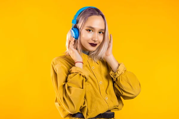 Mulher bonita com cabelo rosa dançando com fones de ouvido no estúdio amarelo — Fotografia de Stock