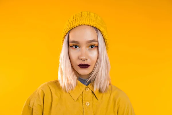 Tamamen sarı giyinmiş genç bir kadın. Stüdyo arka planında siyah makyajlı ve burun piercingli güzel punk kız portresi.. — Stok fotoğraf