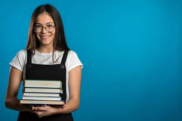 복사 공간. 스튜디오 안에 파란색 배경의 아시아인 여학생 이 도서관에 있는 책들을 보유하고 있다. 웃는 여자, 졸업하게 되서 행복하네. — 스톡 사진