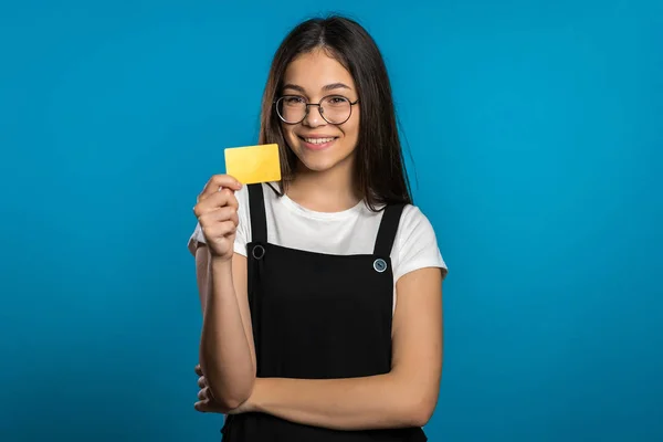 Επιτυχημένη όμορφη ασιατική κοπέλα ματιά στην κάμερα και δείχνει απεριόριστη πιστωτική κάρτα χρυσού σε μπλε φόντο στούντιο. — Φωτογραφία Αρχείου