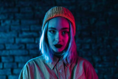 Pembe ve mavi neon ışıklı genç kadın. Duvar arkasında renkli saç stili olan sıradışı güzel punk kızı portresi.