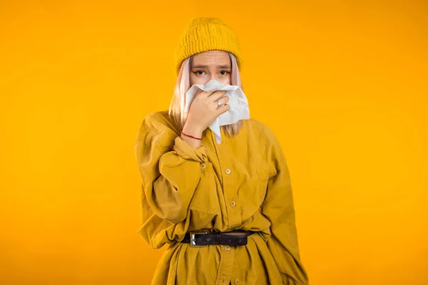 Chica joven estornuda en el tejido. Aislado en la mujer amarilla está enfermo, tiene congestión nasal o secreción nasal y fiebre. Coronavirus, epidemia 2020, concepto de enfermedad . — Foto de Stock