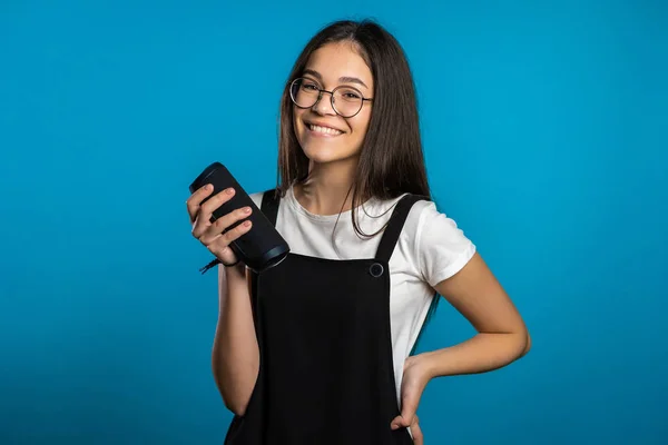 Mignon asiatique femme aux cheveux longs souriant avec haut-parleur portable sans fil en studio sur fond bleu. Musique, concept de danse — Photo