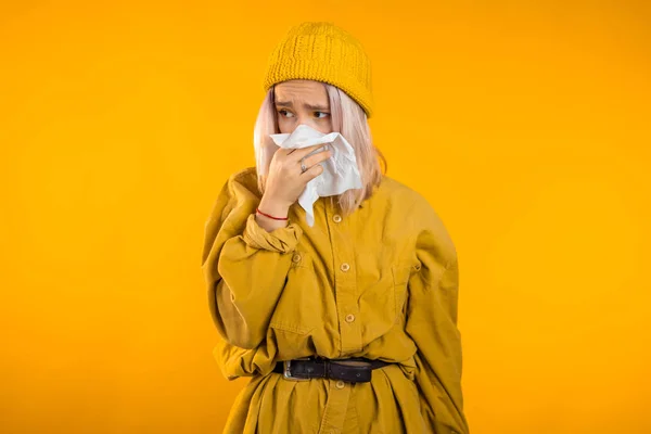 Chica joven estornuda en el tejido. Aislado en la mujer amarilla está enfermo, tiene congestión nasal o secreción nasal y fiebre. Coronavirus, epidemia 2020, concepto de enfermedad . — Foto de Stock