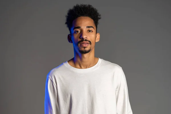 Hombre afroamericano guapo con peinado rizado de moda sobre fondo de estudio gris. Chico alegre sonriendo y mirando a la cámara — Foto de Stock