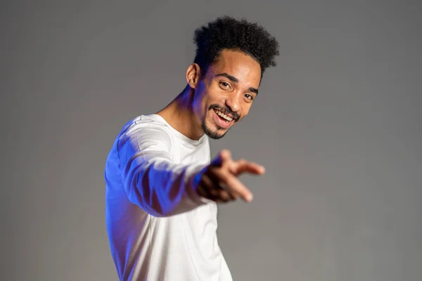 Joven enérgico afroamericano vestido de blanco sonriendo y bailando de buen humor sobre fondo marrón . — Foto de Stock