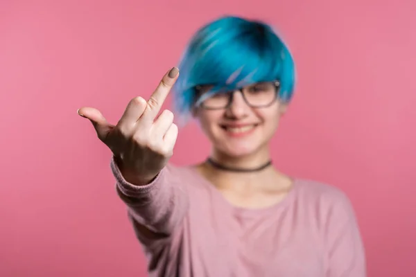 Wanita muda dengan rambut biru di latar belakang merah muda menunjukkan jari tengah gerakan bercinta. Ekspresi negatif, agresi, provokasi . — Stok Foto