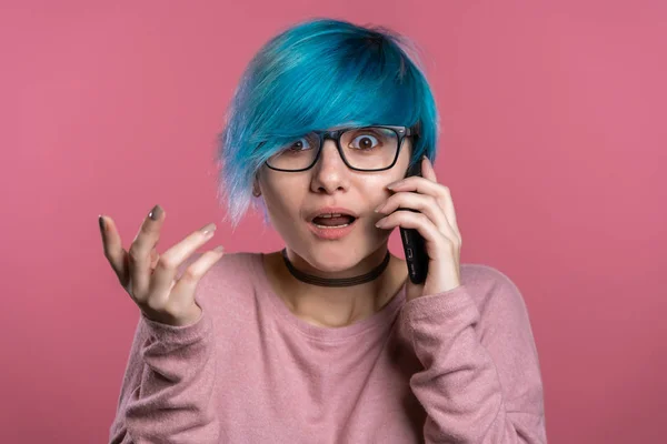 Ungewöhnliche Frau mit blauen Haaren telefoniert mit Smartphone über rosa Wandhintergrund. Mädchen nervös, drückt Schock und Angst über schlechte Nachrichten aus — Stockfoto