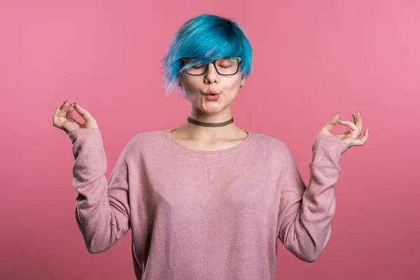 Stock image Calm girl with turquoise hair relaxing, meditating. Woman calms down, breathes deeply with mudra om on pink studio background