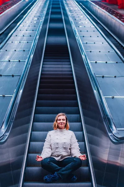 Porträt einer ruhigen Frau, die auf der Rolltreppe einer U-Bahn-Station Yoga-Meditation macht. U-Bahn in Stockholm. — Stockfoto