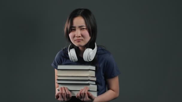 Asian student is dissatisfied with amount of homework and books. Girl with books, she is annoyed, discouraged frustrated by studies. — Stock Video