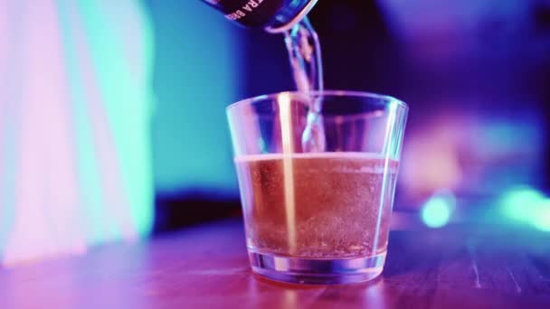 Ung kvinna häller öl ur burken i ett glas i neonljus. Oigenkännlig kvinna med alkoholhaltig dryck i köket på natten. — Stockvideo