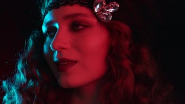 Great Gatsby dönemi tarzında giyinmiş eski moda kadın portresi. Flört ediyor ve arka planda poz veriyor. Vintage, neon ışığı, parti, retro moda konsepti