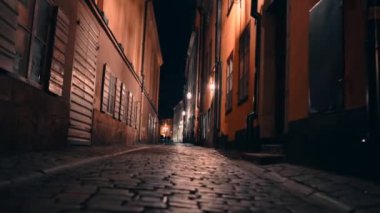 Stockholm, İsveç - 16 Şubat 2020: Steadicam shot, Avrupa gece şehrindeki eski binalar. İskandinavya 'nın dar sokaklarındaki evlerin cepheleri. Kamera kaldırım taşlarının altında ilerliyor