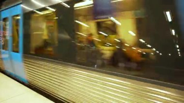 Metro treni hareket ediyor. Yeraltı treni modern metro istasyonundan kalkıyor. Yolunu takip eden insanlarla dolu vagonlar.