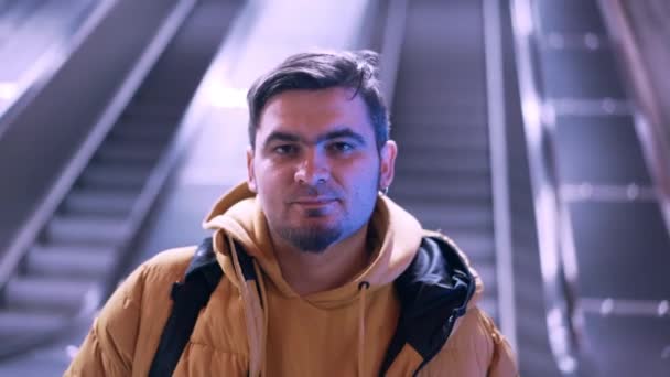 Retrato de homem jovem em pé na estação de metro na escada rolante fundo. Tipo sério com barba. . — Vídeo de Stock