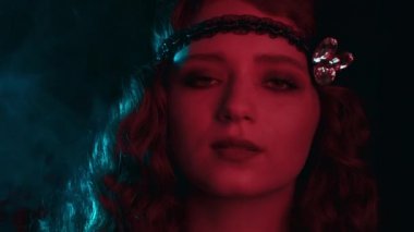 Great Gatsby dönemi tarzında giyinmiş eski moda kadın portresi. Flört ediyor ve arka planda poz veriyor. Vintage, neon ışığı, parti, retro moda konsepti