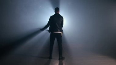 Rock gitaristi arkasını dumanlı stüdyoda ya da sahnede ustaca elektro gitar çalıyor. Karanlık odada tanınmayan bir müzisyenin görüntüsü. Yavaş çekim 4K..