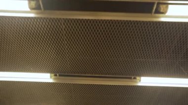 Tavanda floresan beyaz lambalar olan metro istasyonunda hareket var. Endüstriyel yapı. Buharlı çekim.
