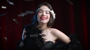 Great Gatsby döneminde giyinmiş, kadife arka planda konfeti yağmuru altında dans eden klasik stil kadın portresi. Kükreyen yirmiler, retro, parti, moda konsepti