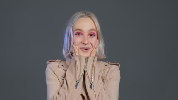 Ganska kvinnliga chockad blond kvinna på grå bakgrund. OMG, wow effekt. Hipsterflicka med glädje. Förvånad glad glad millenial. — Stockvideo