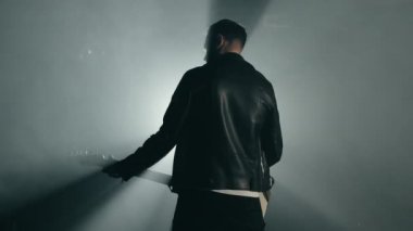 Rock gitaristi arkasını dumanlı stüdyoda ya da sahnede ustaca elektro gitar çalıyor. Karanlık odada tanınmayan bir müzisyenin görüntüsü. Yavaş çekim 4K..