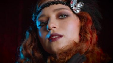 Great Gatsby döneminde giyinmiş eski moda kızıl saçlı bir kadının portresi. Kadife arka planda flört ediyor ve poz veriyor. Kükreyen yirmiler, retro, parti, moda konsepti
