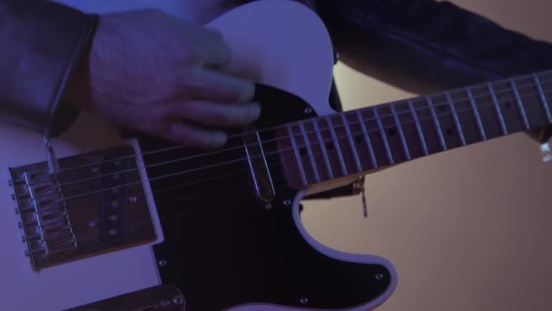 Vista de cerca del músico de rock mans manos magistralmente tocando la guitarra eléctrica. Dedos tocando cuerdas en el centro de atención ahumado durante el concierto en el escenario — Vídeos de Stock