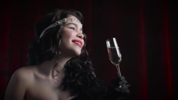 Портрет женщины в винтажном стиле, одетой в эпоху Гэтсби, пьющей шампанское на велюровом фоне. Ревущие двадцатые, ретро, вечеринка, концепция моды — стоковое видео
