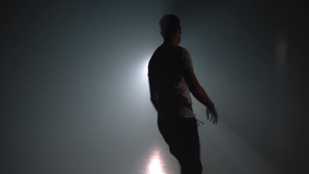 Un joven practicando parkour en un estudio de humo oscuro. Silueta de corredor urbano en acción. Un tipo haciendo volteretas en cámara lenta. Engañando, saltando concepto de práctica . — Vídeos de Stock