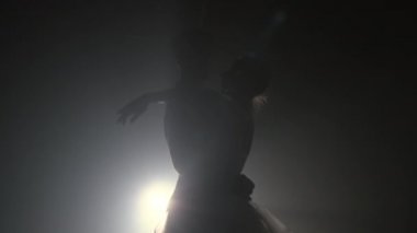 Sahne ışıkları altında dans eden profesyonel bale çifti büyük sahnede sigara içiyor. Sahne ışıkları altında güzel bir genç kadın ve erkek. Duygusal düet koreografik sanat icra ediyor. Ağır çekim. 4k
