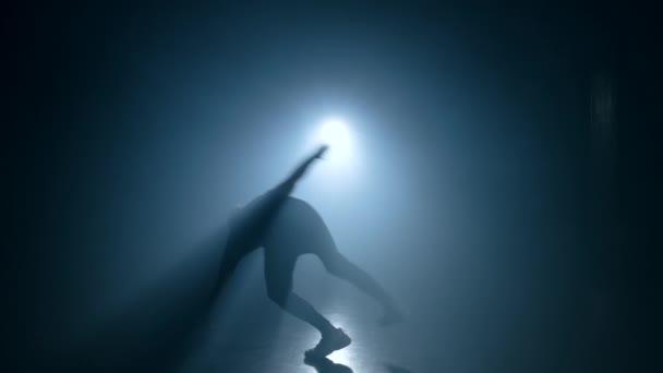 Un joven practicando parkour en un estudio de humo oscuro. Silueta de corredor urbano en acción. Un tipo haciendo volteretas en cámara lenta. Engañando, saltando concepto de práctica . — Vídeos de Stock