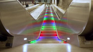 Çok renkli LED gökkuşağı ışıklarıyla yaya yürüyen yürüyen yürüyen yürüyen merdiven insanlar olmadan durmadan yükseliyor. Stockholm metrosunda otomatik merdivenler.