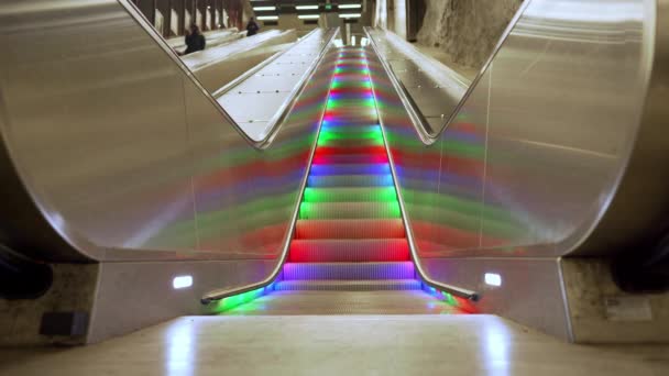 Escalada de travessia de pedestres com luzes de arco-íris LED multicoloridas movendo-se infinitamente sem pessoas. escadas automáticas no metrô de Estocolmo — Vídeo de Stock