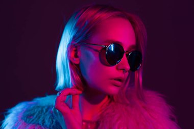 Geceleri neon pembe ve mavi ışıklarıyla alışılmadık bir şekilde görünen genç ve güzel bir kız. Gözlüklü ve güzel lensli ciddi modaya uygun yeniyetme..