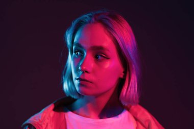 Pembe ve mor neon ışıklı genç kadın. Stüdyo arka planında rengarenk saç stili olan alışılagelmedik güzel bir cazibe ve moda kızının portresi..