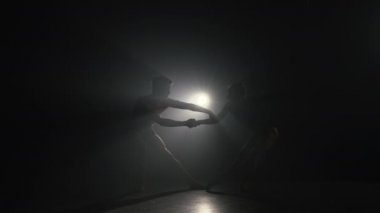 Arka plandaki güzel genç akrobatlar ya da jimnastikçiler. Sahne ışıkları altında dans eden profesyonel bale çifti büyük sahnede sigara içiyor. Duygusal düet koreografik sanat icra ediyor. Ağır çekim. 4k