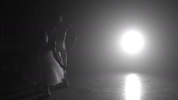 Profesionální baletní pár tančící v reflektorech kouří na velkém pódiu. Krásná mladá žena a muž na pozadí reflektorů. Emocionální duet s choreografickým uměním. Zpomal. 4k — Stock video