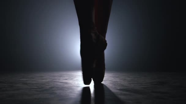 Primer plano de los pies bailarines de ballet en punta calentada antes de actuar en el escenario. Bailarina practica en piso en estudio oscuro con humo. Movimiento lento . — Vídeos de Stock