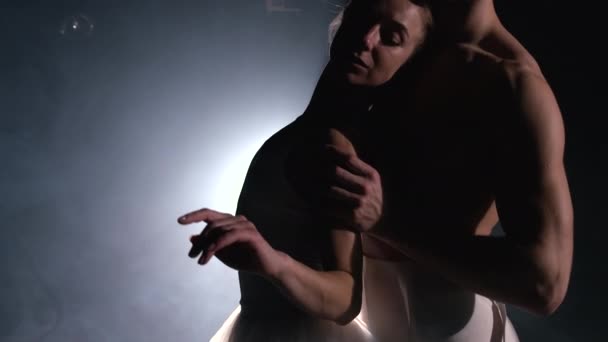 Sahne ışıkları altında dans eden profesyonel bale çifti büyük sahnede sigara içiyor. Sahne ışıkları altında güzel bir genç kadın ve erkek. Duygusal düet koreografik sanat icra ediyor. Ağır çekim. 4k — Stok video